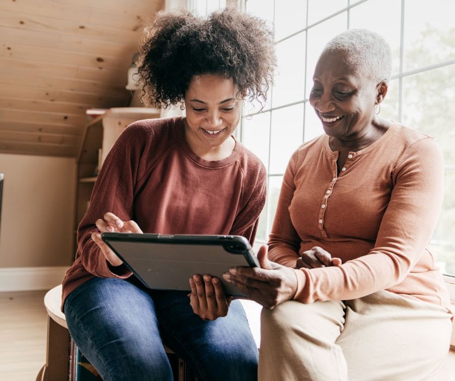 Two women reviewing a care plan together on a tablet.